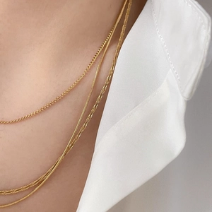 Close-up of triple-layered golden necklace with snake bone and rectangle links on model