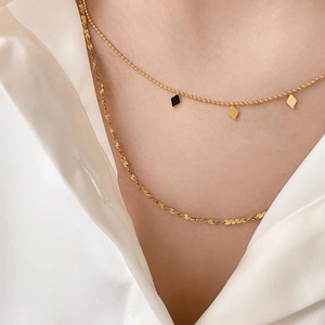 Close-up of layered gold necklace with diamond charm and textured flat snake chain