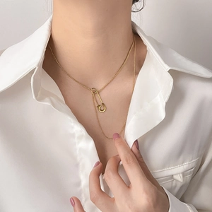 Detailed view of a gold paperclip pendant on a delicate cross chain for a minimalist look