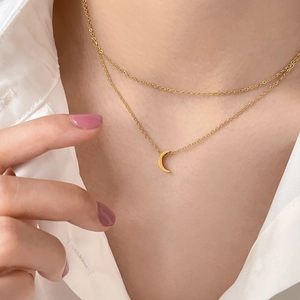 Double layered gold necklace with minimalist crescent moon pendant shown on collarbone