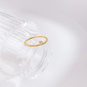 Détail d'une bague plaquée or 18 carats avec un petit zircon rond sur un anneau fin