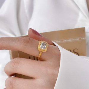 Gros plan d'une bague en titane plaqué or 18 carats avec zircon carré sur soie blanche