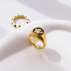 Close-up of golden signet ring with relief angel motif on black round base