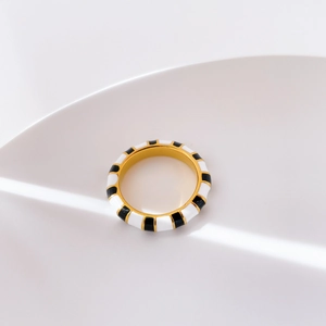 Detail of gold ring with black and white enamel checkerboard pattern under elegant lighting