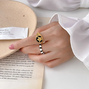 Macro view of gold angel relief on black oval ring with black and white enamel band