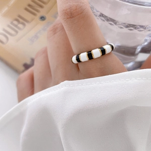 Close-up of black and white enamel ring with gold metal spacers on a finger