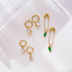Detailed set of gold earrings with green emerald zircon drops and safety pin designs