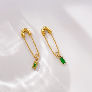 Detail of safety pin earrings in gold finish featuring rectangular green zircon drops
