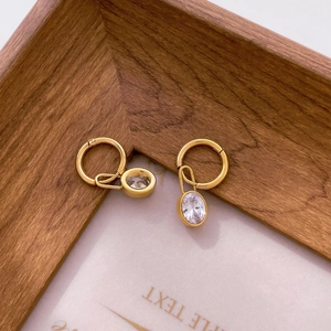 Detailed close-up of gold dangle earrings featuring oval-cut clear cubic zirconia stones