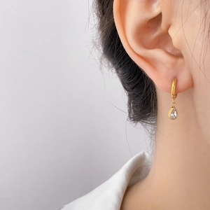 Close-up of gold drop earring with teardrop crystal on ear to show material detail