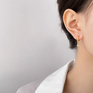 Detail of elegant gold drop earring with a clear teardrop stone on model