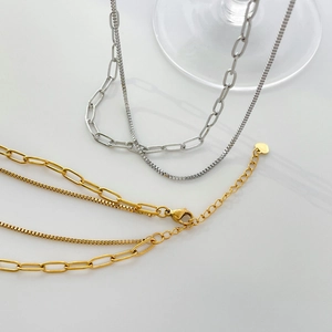 Vue détaillée de chaînes multicouches or et argent avec pendentif cœur et fermoir homard