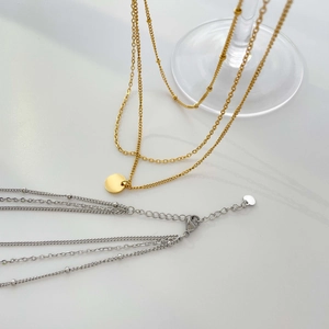 Détail d'un collier à plusieurs rangs or et argent avec pendentif sur base en verre