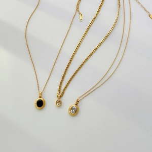 Close-up of three gold pendant necklaces with oval sapphire and K18 hallmark tag