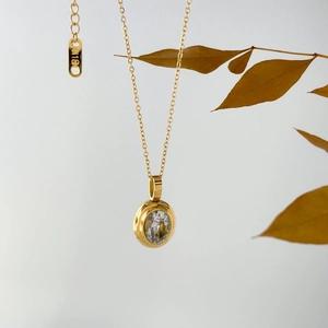 Detail of 18K gold necklace showing K18 hallmark and round brilliant zircon pendant