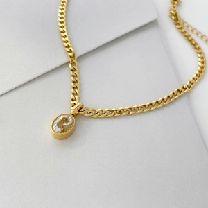 Detail of gold Cuban chain necklace with oval clear crystal pendant and adjustable link