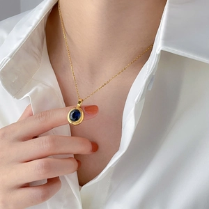 Geometric oval sapphire and gold necklace shown worn by a model in a close-up view