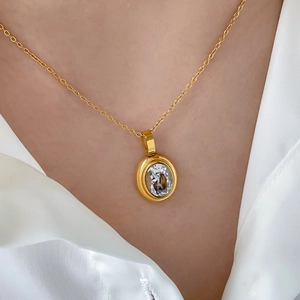 Detail of elegant gold oval pendant necklace featuring a brilliant clear faceted stone