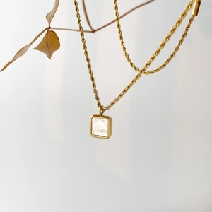Detailansicht eines quadratischen Perlmutt-Anhängers an einer goldenen Kordelkette