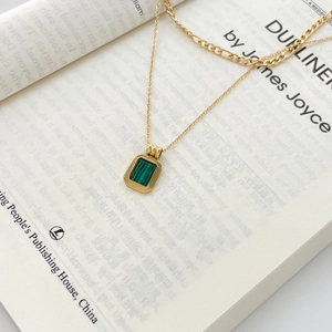Details einer doppellagigen Goldkette mit Malachit-Anhänger auf einem Vintage-Buch