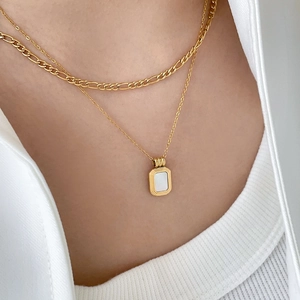 Detail einer geschichteten Goldkette mit rechteckigem weißem Perlmutt-Anhänger