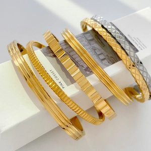 Macro detail of various gold and silver metal bracelets showing textured geometric patterns