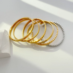 Detailed stack of 18K gold and silver plated titanium steel bangles with textured patterns