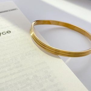 Macro shot of 18K gold plated titanium steel bangle with three parallel fine groove textures