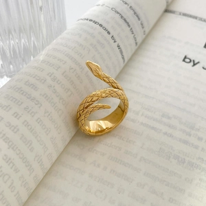 Primer plano de un anillo de serpiente dorado con escamas sobre un libro