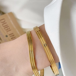 Set of two 18K gold plated titanium steel bangles with ribbed and grooved textures