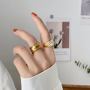 Primer plano de anillos vintage dorados con banda lisa y patrón ondulado de esmalte blanco