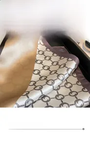 Detail view of the fine stitched edge on a pearl grey silk scarf with logo print