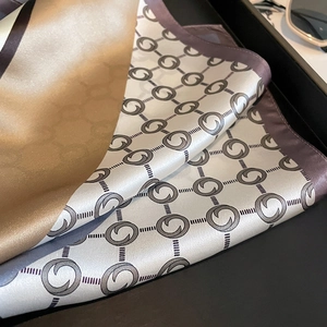 Silk square scarf with geometric pattern in gold, ivory and lilac on a dark tray