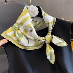 Elegante pañuelo de seda con flores y rayas amarillo-verde anudado como bufanda de moda