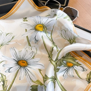 Detailed view of silk scarf featuring realistic daisy prints and striped border edges