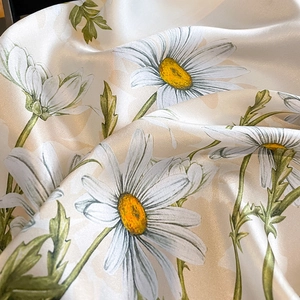 Detailed close-up of glossy mulberry silk scarf with yellow daisy print and soft folds