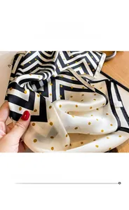 Detailed view of silk scarf with black and white zigzag patterns and golden polka dots