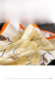 Détail d'un foulard en soie montrant un bord roulé orange et un motif de magnolia