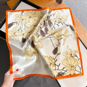 Carré en soie avec imprimé magnolia jaune et ourlet orange vif sur fond en bois