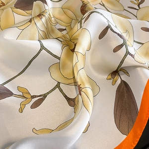 Macro de foulard en soie montrant un motif de magnolia et une bordure orange vif