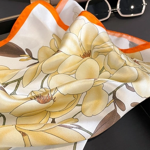 Vue détaillée du foulard en soie magnolia avec ourlet orange et texture lisse