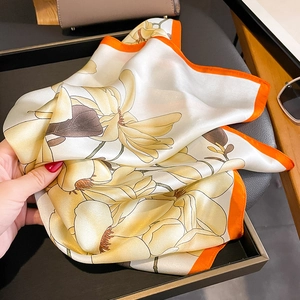 Carré en soie élégant motif magnolia avec bordure orange et texture fluide et douce