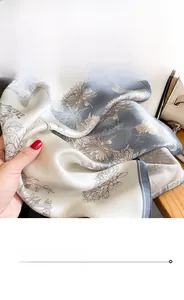 Detailed view of floral silk scarf featuring fine stitching and smooth satin texture