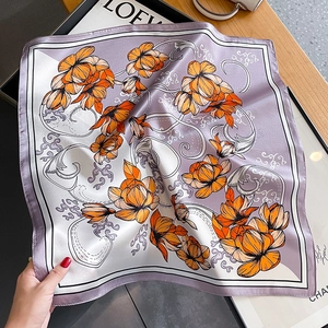 Elegant floral silk square scarf with orange blooms and purple borders on a desk