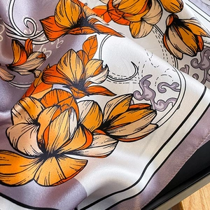 Detailed macro view of silk scarf texture with orange floral pattern and cloud motifs