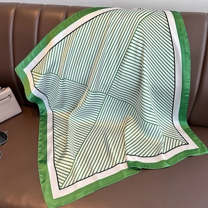 Élégant foulard carré en soie à rayures vertes et blanches sur une surface en cuir