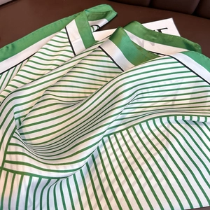 Gros plan du foulard en soie à rayures vertes et blanches avec un éclat de satin