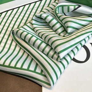Gros plan du foulard en soie à rayures vertes et blanches avec un éclat satiné élégant