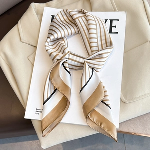 Élégant foulard en satin rayé or et blanc pour femme sur un blazer beige chic