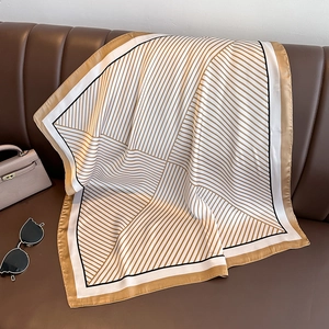 Élégant foulard carré en satin de soie à rayures drapé sur un canapé en cuir